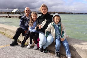 Makenzie Van Eyk, center, with her fourth-grade teacher, Roland St. Pierre, and her two children, Scarlet, 9, and Huxley, 6, on the pier where Van Eyk tossed a message in a bottle in the lake as part of a school assignment in 1998. Nearly three decades later, a kindergarten student at the same school Van Eyk attended found it.